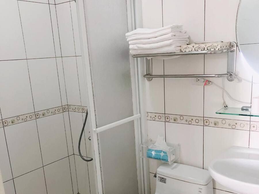A bathroom with a toilet, a glass shower enclosure, a sink, and a towel rack.