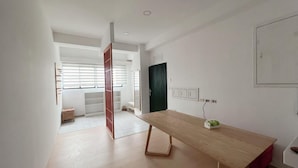 Una habitación amplia con piso de madera, una mesa grande y un armario con puertas correderas.
