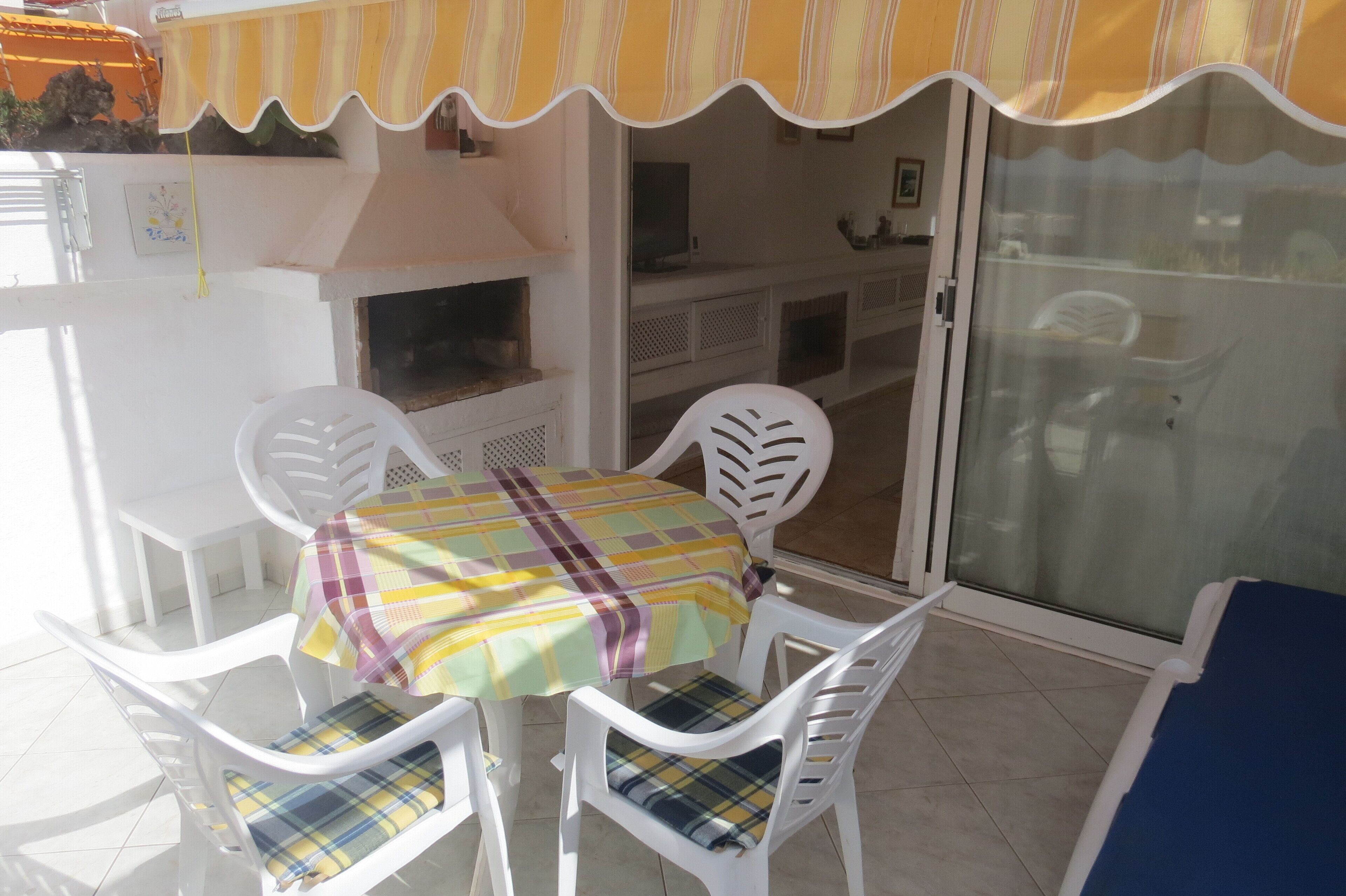 Un espace patio aménagé avec une table et des chaises, un barbecue et une porte-fenêtre coulissante.