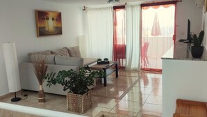 A living room with a sofa, a coffee table, a potted plant, and a painting on the wall. - Vv Apartamento Gran Vista Colony Club (Puerto del Carmen)