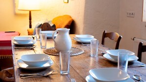 Een eettafel gedekt met witte borden, kommen en een karaf, omringd door stoelen.
