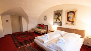 Een hotelkamer met een groot bed, een bank, een rood tapijt en twee posters aan de muur.