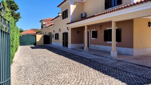 A building with a cobblestone driveway leading to a gated entrance. - Modern, large and beautiful villa with pool/garden in Azeitão south of Lisbon. (Azeitão, Setubal)