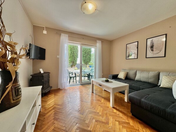 A living room with a sofa, a coffee table, a TV, and a fireplace. - Apartment DiSente °1 in Krk, family friendly, close to the center, dogs allowed (Krk)