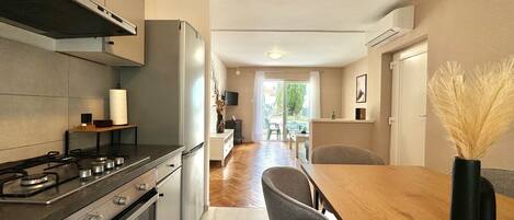 A modern kitchen with a gas stove, oven, and a dining area with a wooden table and chairs.