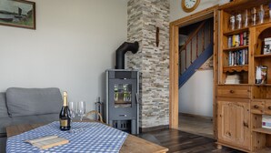 Ein gemütliches Wohnzimmer mit Kamin, einer Bücherwand und einem Essbereich mit Tisch für zwei Personen.