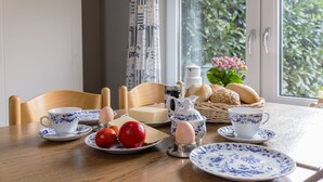 Ein Frühstückstisch mit Tasse, Untertasse, Eiern, Tomaten und Brot.