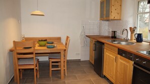 Une cuisine avec des meubles en bois, un lave-vaisselle et une table à manger avec des chaises.