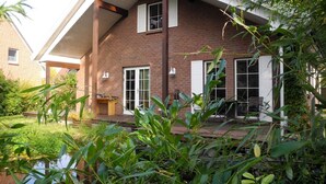 Una casa de maó de dos pisos amb un porxo cobert i una petita zona de jardí.