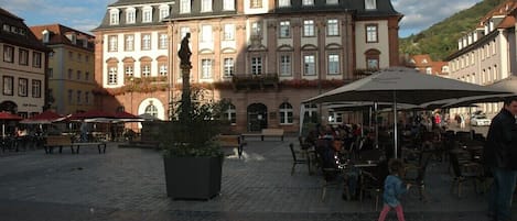 Un edificio histórico con un patio central, asientos al aire libre y una estatua.