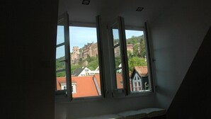 A room with a large window overlooking a historic building and surrounding houses. - Old Town Apartment "Himmelreich" (Heidelberg)