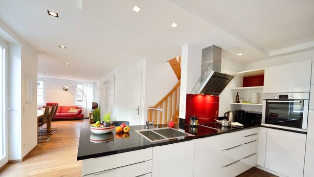 A modern kitchen with white cabinets, a black countertop, and stainless steel appliances. - Old Town Apartment "Himmelreich" (Heidelberg)