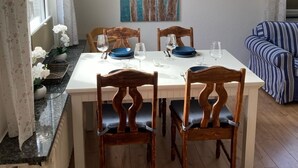 A dining area with a white table, four wooden chairs, and a painting of seagulls on a wall. - Apartment with large terrace only 150 m to the beach. Renovated in 2024 (Grömitz)