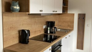 A modern kitchen with wooden countertops, white cabinets, a built-in oven, and a coffee maker. - Apartment with large terrace only 150 m to the beach. Renovated in 2024 (Grömitz)