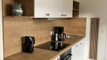 Une cuisine moderne avec des plans de travail en bois, des armoires blanches, un four encastré et une machine à café.