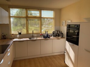 A kitchen with a sink, stove, and window with blinds.