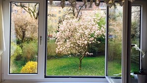 Een kamer met een groot raam met uitzicht op een tuin met bloeiende bomen.