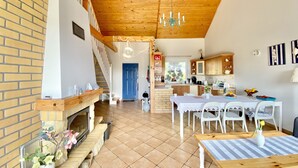 Una cocina amplia con armarios de madera, un comedor con mesa y sillas, y una escalera que sube a un nivel superior.