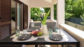 Una mesa de comedor dispuesta con platos, cubiertos y un centro de mesa con flores y frutas.