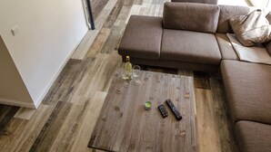 Un salon moderne avec un canapé d’angle marron, une table basse en bois et un coin repas comprenant une table et des chaises.
