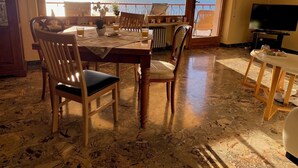 A dining area with a table and chairs, a TV, and a view of the sea. - Romantic villa with a fantastic view of Lake Garda (Toscolano Maderno)