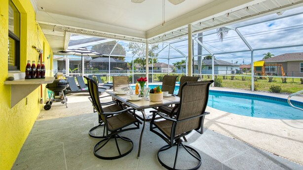 A covered patio with a pool, outdoor seating, and a grill area. - Villa Sunsplash-Modern, south-facing, large pool- perfect for families (Cape Coral)
