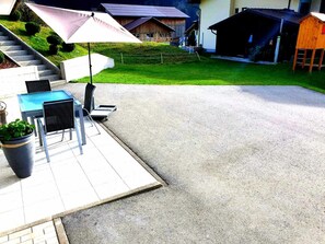 Un espace patio avec des sièges d’extérieur, un escalier menant à un bâtiment et une petite structure en bois.