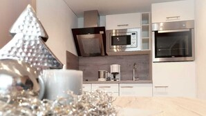 Une cuisine moderne équipée d’appareils électroménagers en acier inoxydable, d’une machine à café et agrémentée d’un arbre décoratif en argent.