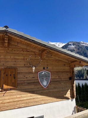 Une cabane en bois avec une pancarte indiquant « Chalet Kaprun » et un crâne de cerf accroché au mur.