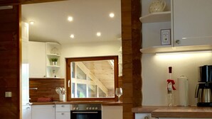 A modern kitchen with white cabinets, a built-in oven, and a wooden ceiling.