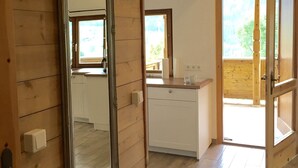 A wooden interior with a large mirror, a kitchen area, and a door leading outside.
