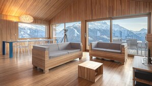 A modern interior with wooden paneling, a large window overlooking snowy mountains, and a cozy seating area. - Exclusive design chalet on 1 800 meters, 4-6 pers.,  above Törbel (Törbel)