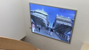 A staircase with a wooden handrail and a wall-mounted picture of a cruise ship. - Exclusive apartment in Warnemünde, 150m to the beach, 2 bathrooms, 2 bedrooms, sauna, WLAN and much more. (Rostock)