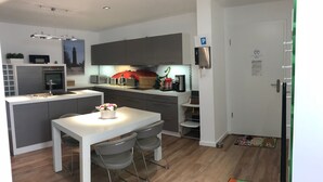 A modern kitchen with grey cabinets, a white countertop, and a dining area with a table and chairs. - Exclusive apartment in Warnemünde, 150m to the beach, 2 bathrooms, 2 bedrooms, sauna, WLAN and much more. (Rostock)