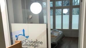 A room with a bed, a window with blinds, a circular light fixture, and a glass door with a logo. - Exclusive apartment in Warnemünde, 150m to the beach, 2 bathrooms, 2 bedrooms, sauna, WLAN and much more. (Rostock)
