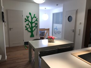 A modern room with a dining table, chairs, a decorative tree wall art, and a sign for 'CruiseLine Lounge'. - Exclusive apartment in Warnemünde, 150m to the beach, 2 bathrooms, 2 bedrooms, sauna, WLAN and much more. (Rostock)