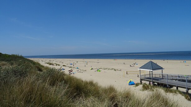 Ein Strand mit Zelten und einem Rettungsturm.