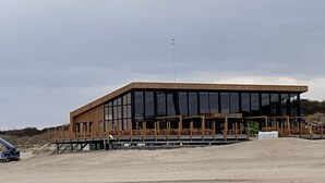 Ein modernes Gebäude mit flachem Dach, großen Fenstern und einer Holzfassade.