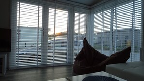 Ein Zimmer mit großen Fenstern, einem Sofa und einem Sitzsack.