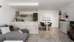 A modern living room with a grey sofa, a small white table, and a fireplace. - Apartment with stunning sea views and views of the island of Cres (Mali Kosi)