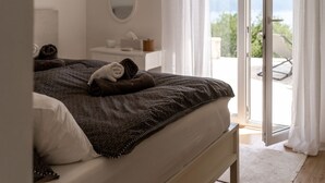 A bedroom with a bed, a bedside table, a mirror, and a view of the outdoors. - Apartment with stunning sea views and views of the island of Cres (Mali Kosi)