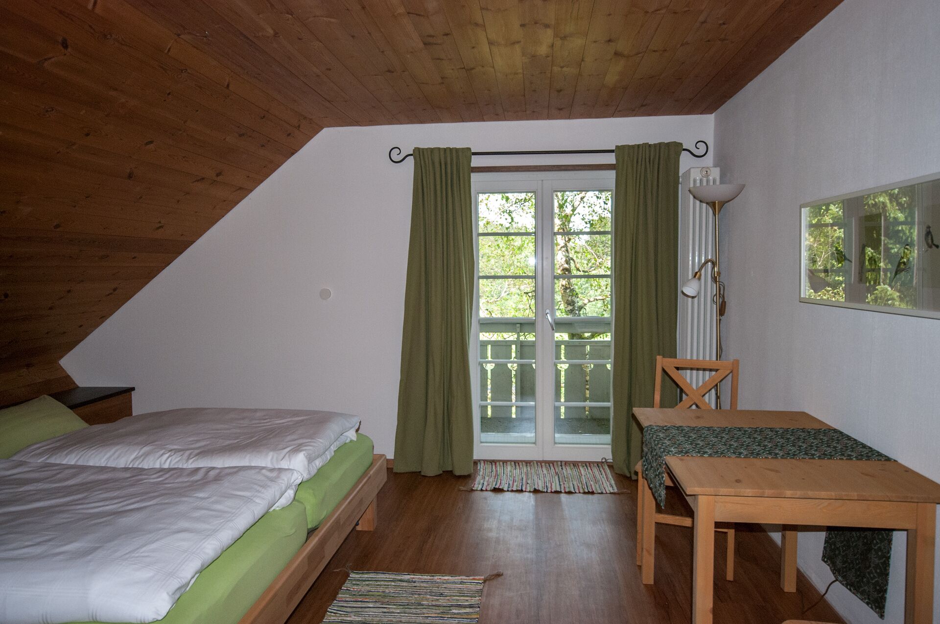 Un dormitorio con una cama, una mesa de madera y una ventana con cortinas.
