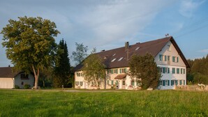 Een ruim, twee verdiepingen tellend huis met een schuin dak, veel ramen en een verzorgd gazon op de voorgrond.
