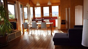 A wooden interior with a dining area, kitchen, and seating space. - Pure relaxation! Holiday home: integrated into the nature with modern interior! (Frickingen-Altheim)