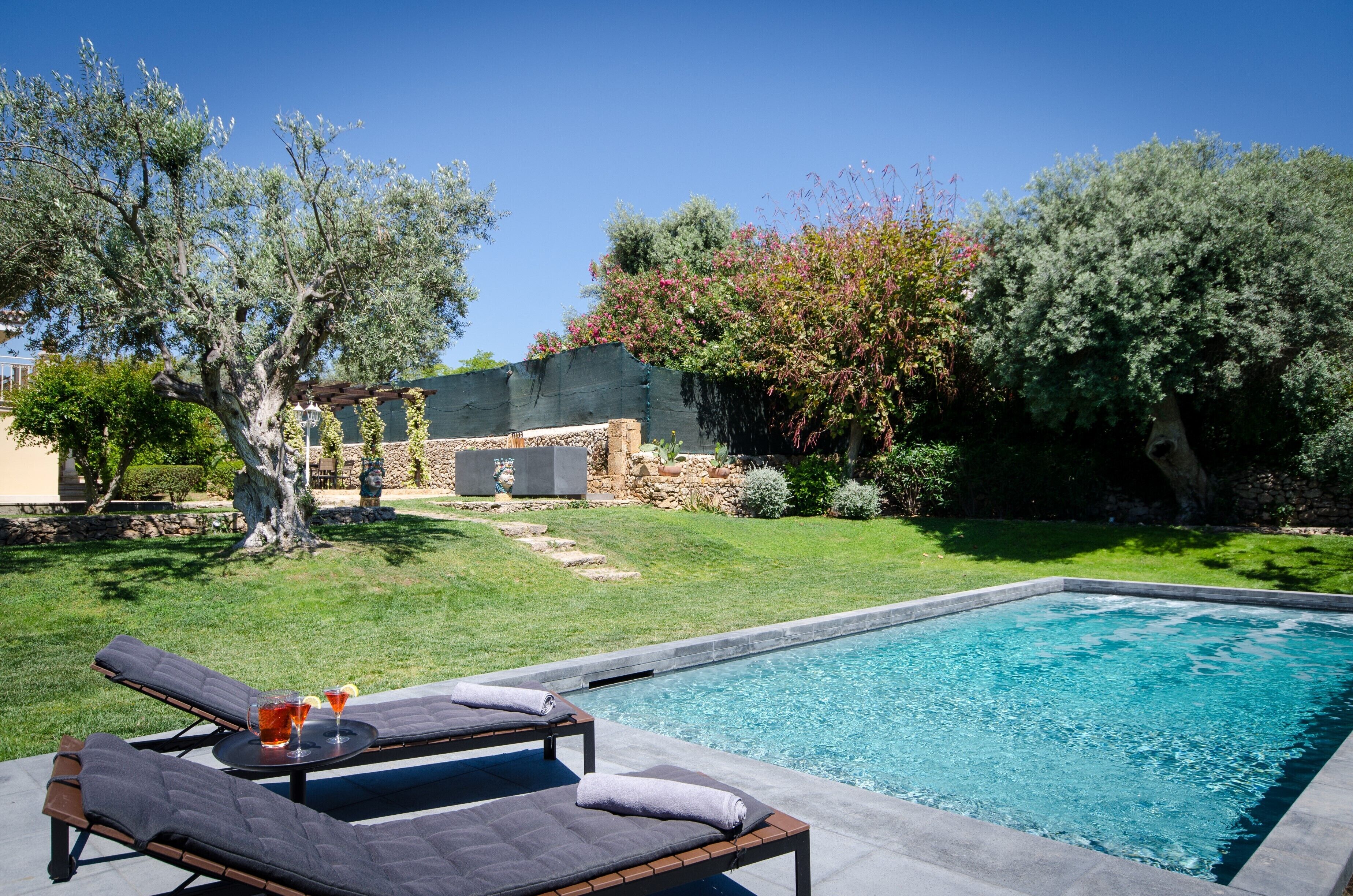 Une piscine avec des chaises longues et un mur de pierre en arrière-plan.