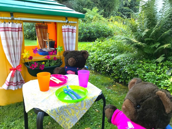 A small playhouse with a table set for a meal, surrounded by greenery. - Family-friendly home for 10 persons, big garden, Fireplace, 4 km ski carousel. (Winterberg)