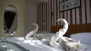 Ein Hotelzimmer mit einem Bett, einem Spiegel, Streifenmuster-Tapete und einem gerahmten Bild an der Wand.
