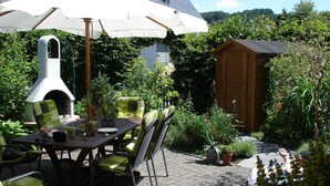 Eine Terrasse im Freien mit einem Tisch, Stühlen und einem Pizzaofen.