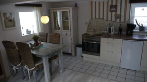 A kitchen with a dining table, chairs, a stove, oven, and a small refrigerator.