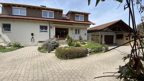 Ein zweistöckiges Haus mit gepflasterter Auffahrt, einer Veranda und einem Garten.